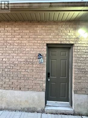Waterloo apartment for rent - A brown door with a black handle and a black lamp on the wall.