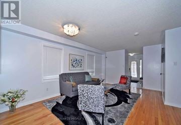 Vaughan (Vellore Village) apartment for rent - A living room with a grey couch and a black and white patterned chair.