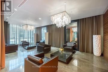 Toronto (University) condo for rent - A modern living room with a glass table and brown leather couches.