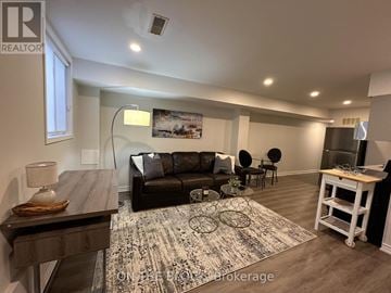 Toronto (Greenwood-Coxwell) townhouse for rent - A living room with a black couch and a rug on the floor.