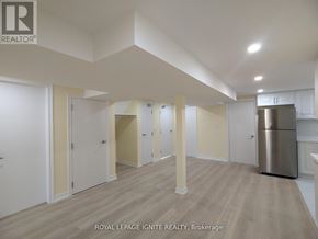 Toronto (Tam O'shanter-Sullivan) apartment for rent - A spacious room with wooden flooring and white walls, with a stainless steel refrigerator on the right side.