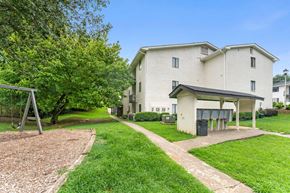 Atlanta apartment for rent - a white building with a playground and a tree