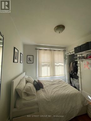 Kingston (Central City East) apartment for rent - A bedroom with a bed, a window with curtains, and a shelf with various items.