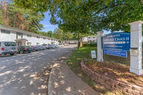 Clarkston apartment for rent - a building with a blue sign and cars parked in front of it