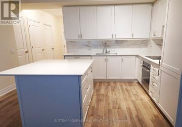 Vaughan (Concord) condo for rent - A kitchen with white cabinets and a blue island.