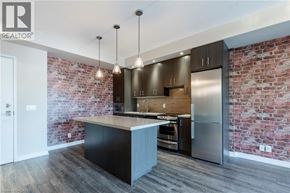 Burlington condo for rent - A modern kitchen with a brick wall and stainless steel appliances.