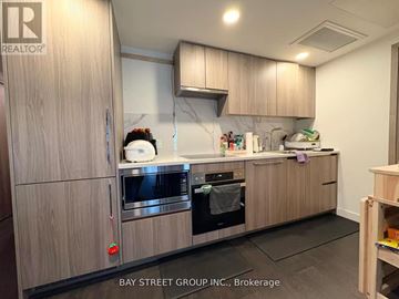 Toronto (Waterfront Communities) condo for rent - A kitchen with wooden cabinets and a marble backsplash.