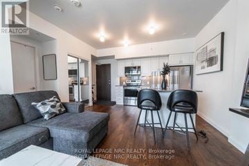 Niagara Falls (Oldfield) condo for rent - A living room with a grey couch and two black chairs.