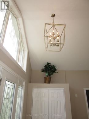 Niagara Falls (Schisler) apartment for rent - A chandelier hangs in a room with white walls and a plant in a basket on a cabinet.