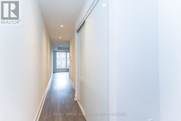 Toronto (The Beaches) condo for rent - A living room with a grey couch, a small table with a vase of flowers, and a rug with a geometric pattern.