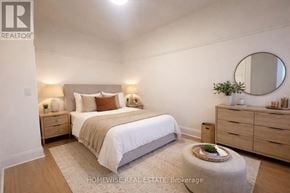 Toronto (South Parkdale) multi-family for rent - A bedroom with a bed, nightstands, and a round mirror on the wall.