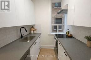 Toronto (South Parkdale) multi-family for rent - A kitchen with white cabinets and a grey countertop.
