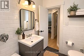 Toronto (South Parkdale) multi-family for rent - A bathroom with a sink, mirror, and toilet paper holder.