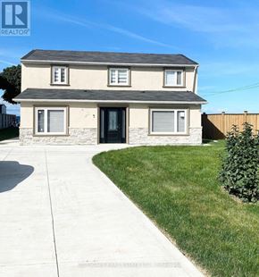Hamilton (Lakeshore) apartment for rent - A house with a grey roof and a black door is surrounded by a white fence and green grass.