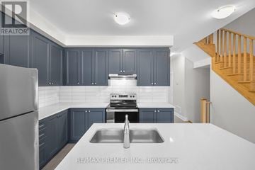 Kawartha Lakes (Lindsay) townhouse for rent - A kitchen with dark blue cabinets and a stainless steel refrigerator.