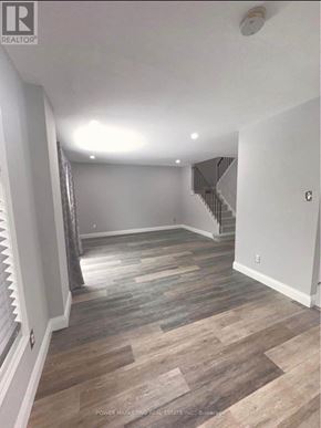 Ottawa apartment for rent - A room with wooden flooring and a staircase in the background.
