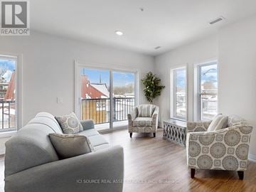 Kawartha Lakes (Lindsay) multi-family for rent - A living room with a grey couch and a patterned armchair.