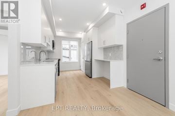 Ottawa multi-family for rent - A modern kitchen with white cabinets and a wooden floor.
