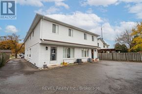 Pelham (Fonthill) fourplex for rent - A white house with a REVEL Realty Inc. sign in the foreground.