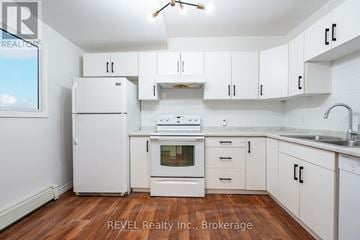 Niagara Falls (Downtown) triplex for rent - A white kitchen with wooden floors and white appliances.