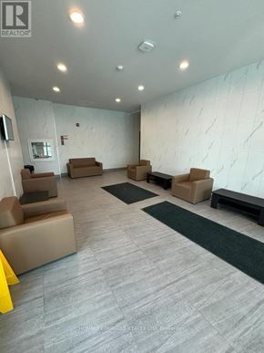 Kingston (Central City East) condo for rent - A spacious waiting area with beige couches and a marble wall.