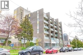 Waterloo condo for rent - A building with the number 63 on it is behind a row of parked cars.