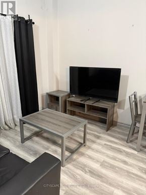 Waterloo condo for rent - A black television is on a wooden stand in a room with a grey floor.