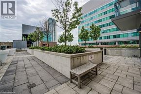 Kitchener condo for rent - A bench with a no-smoking sign on it sits in the middle of a paved area.