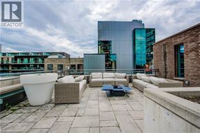 Kitchener condo for rent - A modern outdoor seating area with a large white planter and a blue mat on the floor.