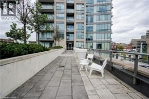 Kitchener condo for rent - A balcony with two chairs and a table is in front of a building with the word REALTOR on it.