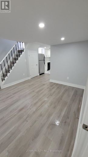 Pickering (Village East) apartment for rent - A spacious room with a staircase and a door in the background.