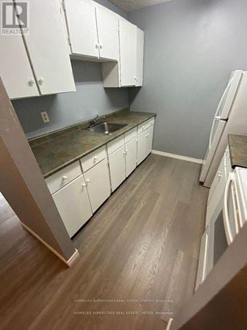 Niagara Falls (Ascot) multi-family for rent - A kitchen with white cabinets and a wooden floor.