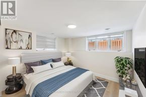 Ottawa apartment for rent - A bedroom with a bed, a lamp, a plant, and a painting on the wall.