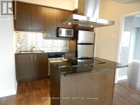 Mississauga (City Centre) condo for rent - A modern kitchen with stainless steel appliances and wooden cabinets.