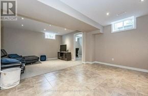 Kitchener apartment for rent - A living room with a black couch, a white rug, and a wooden entertainment center.