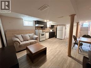 Windsor apartment for rent - A living room with a couch, a coffee table, and a kitchen area in the background.