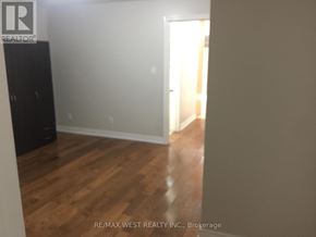 Toronto (Weston-Pellam Park) apartment for rent - A room with wooden flooring and a white wall with a doorway leading to another room.
