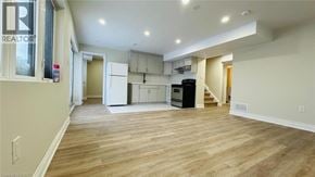 Kitchener apartment for rent - A spacious living area with wood flooring and a kitchen in the background.