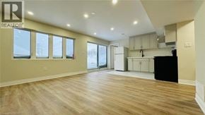 Kitchener apartment for rent - A spacious room with wooden flooring and a large window.
