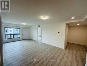 Windsor condo for rent - A spacious room with wooden flooring and white walls, with a window and a door visible.