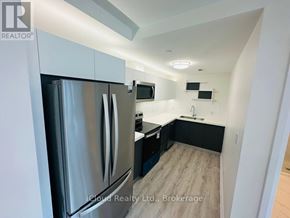 Windsor condo for rent - A modern kitchen with a stainless steel refrigerator and wooden flooring.