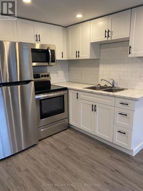 Welland (Prince Charles) multi-family for rent - A kitchen with white cabinets and a stainless steel refrigerator.