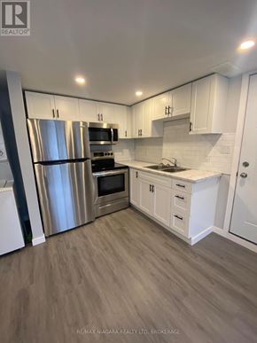 Welland (Prince Charles) multi-family for rent - A modern kitchen with white cabinets and stainless steel appliances.