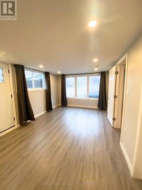 Welland (Prince Charles) multi-family for rent - A spacious room with wooden flooring and large windows.