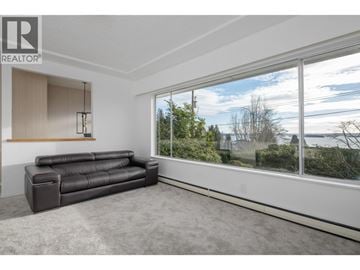 West Vancouver apartment for rent - A living room with a black leather sofa and a large window.