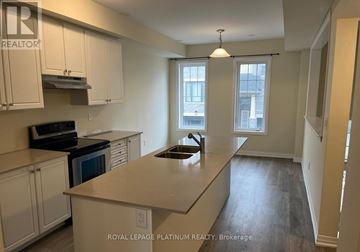 Hamilton (Stoney Creek) townhouse for rent - A kitchen with white cabinets and a black stove top oven.