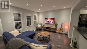 Brampton (Fletcher's West) townhouse for rent - A living room with a blue couch, a wooden coffee table, a flat screen TV, and a guitar.