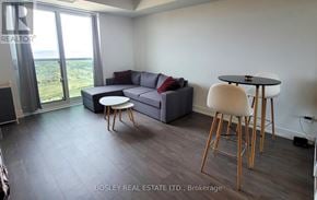 Oshawa (Windfields) house for rent - A living room with a grey couch, a black table, and a white chair.