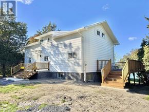 Prince Edward County (South Marysburgh) apartment for rent - A white house with a wooden deck and stairs leading to the front door.
