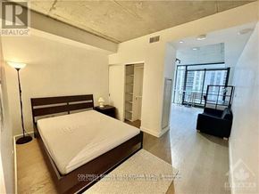 Ottawa condo for rent - A bedroom with a large bed and a balcony.